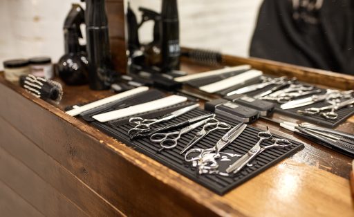 barber tools on wooden shelf and mirror in barbershop.